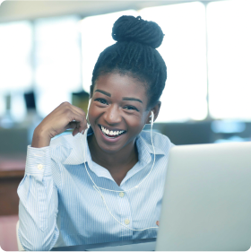 A teenage girl with headphones smiling while sitting in front of a computer